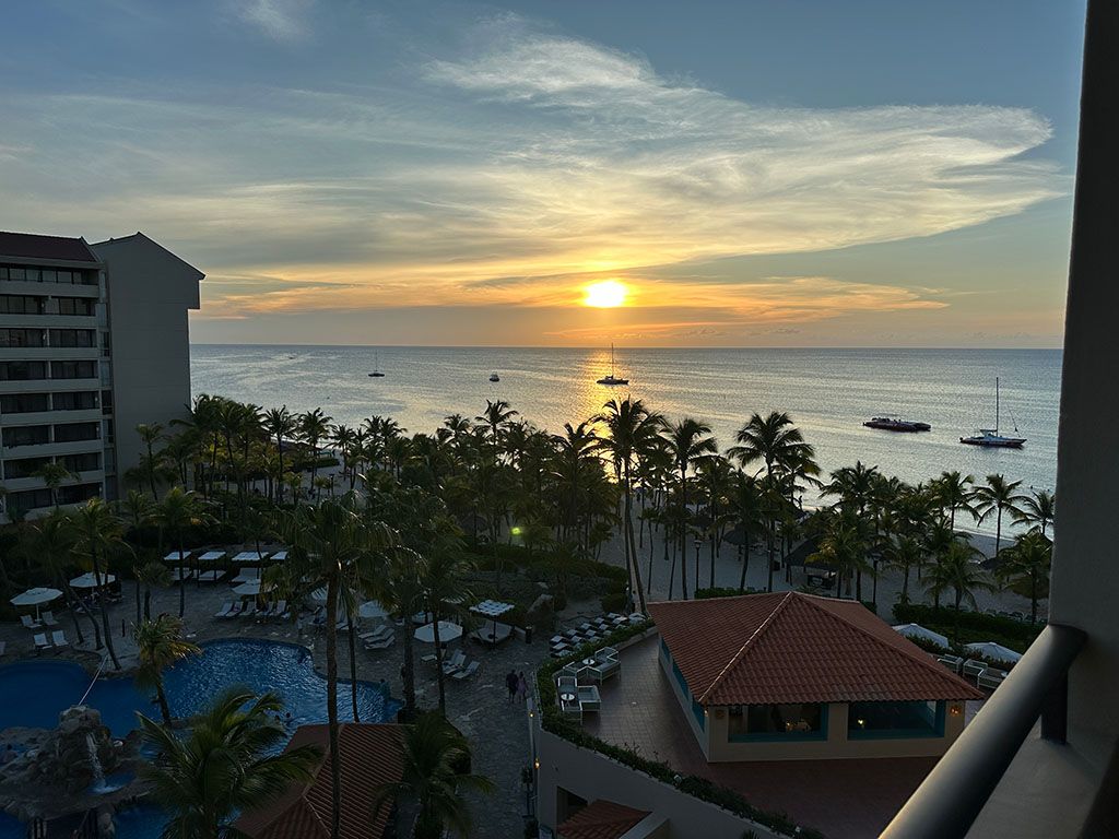 A picture of the sun setting over the ocean with the resort in the foreground